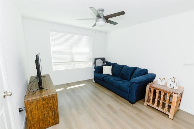 living room featuring ceiling fan, baseboards, and light wood-style flooring