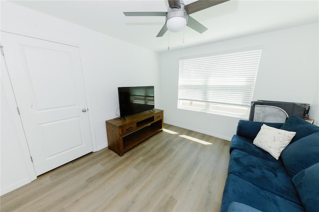 living room with light wood finished floors, baseboards, and ceiling fan