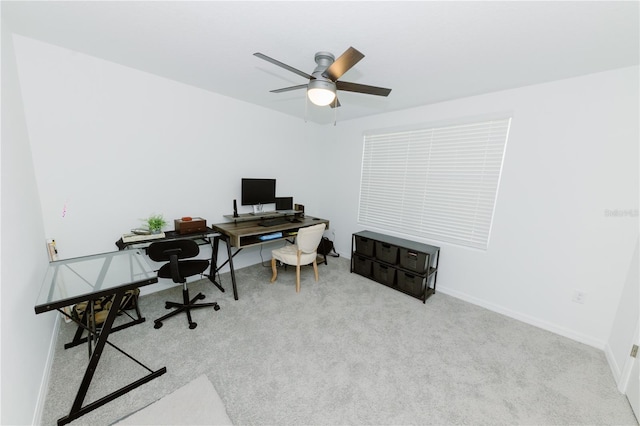 carpeted office space featuring a ceiling fan and baseboards