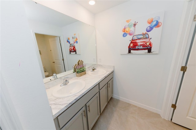 full bath with a sink, baseboards, toilet, and double vanity