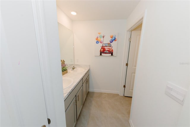 full bath with a sink, baseboards, double vanity, and tile patterned flooring