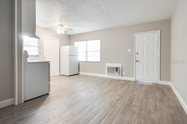 unfurnished living room with washer / clothes dryer, a ceiling fan, baseboards, and light wood finished floors