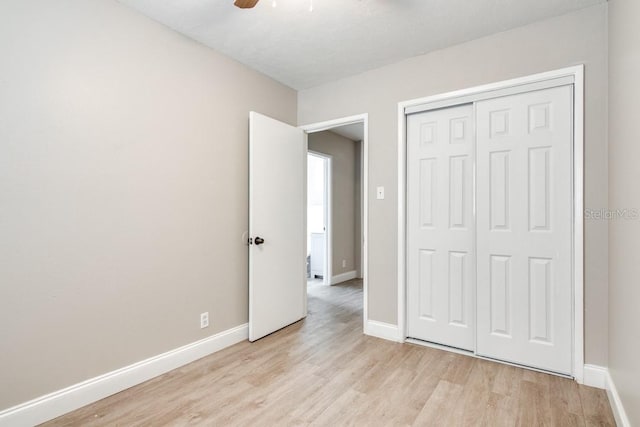 unfurnished bedroom featuring a closet, baseboards, light wood-style flooring, and a ceiling fan