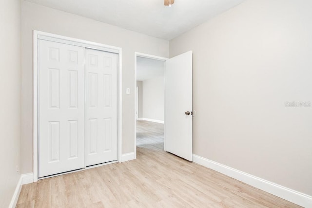 unfurnished bedroom with light wood-type flooring, baseboards, a closet, and ceiling fan