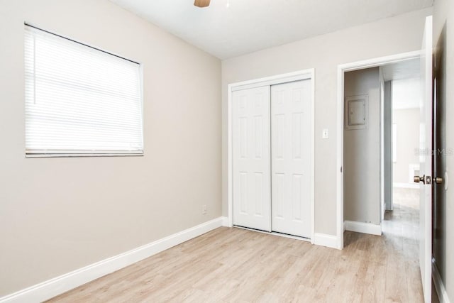 unfurnished bedroom featuring a closet, baseboards, light wood-style floors, and a ceiling fan