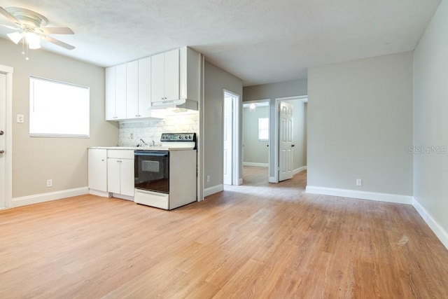 kitchen with light wood finished floors, under cabinet range hood, decorative backsplash, range with electric stovetop, and white cabinetry