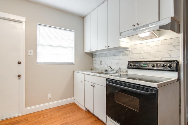 kitchen with range with electric cooktop, baseboards, under cabinet range hood, decorative backsplash, and a sink