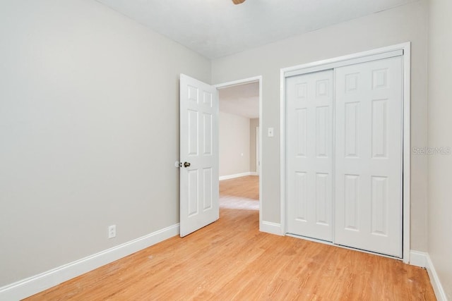 unfurnished bedroom featuring a closet, baseboards, and light wood-style floors