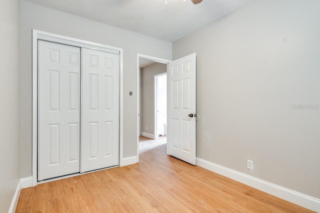 unfurnished bedroom with a closet, baseboards, light wood finished floors, and ceiling fan