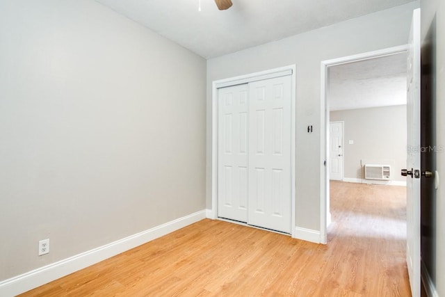 unfurnished bedroom featuring light wood-style flooring, a ceiling fan, baseboards, and a closet