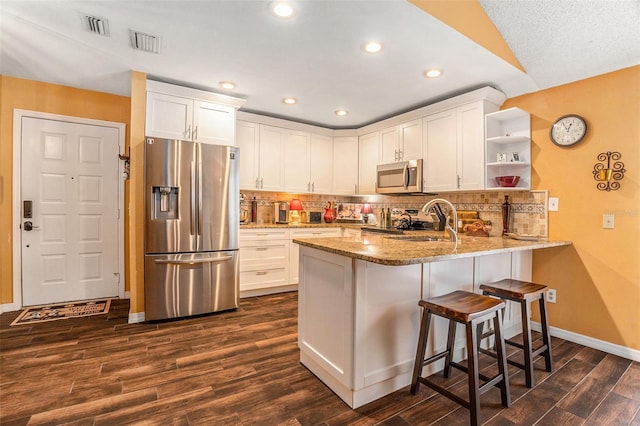 kitchen with visible vents, open shelves, stainless steel appliances, a peninsula, and light stone countertops