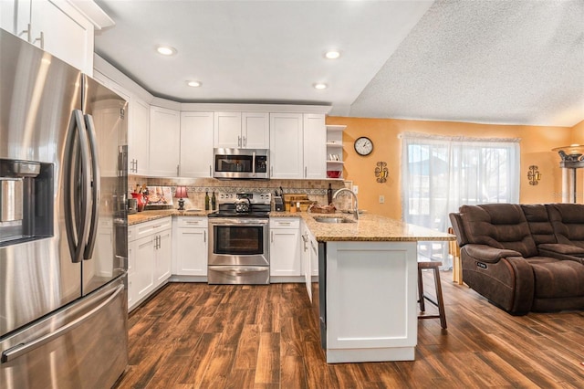 kitchen featuring open shelves, open floor plan, white cabinetry, stainless steel appliances, and a peninsula