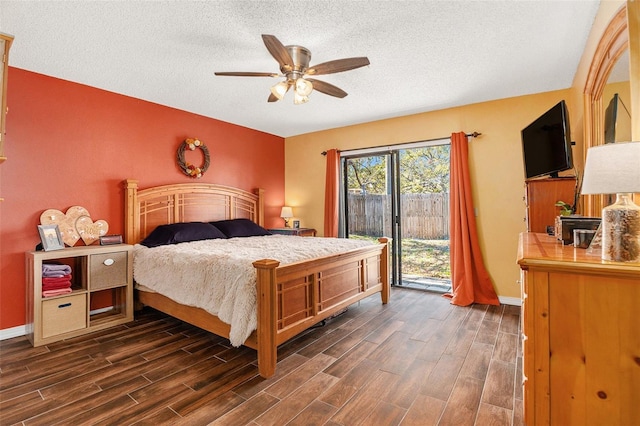 bedroom featuring dark wood-style flooring, a textured ceiling, baseboards, and access to outside