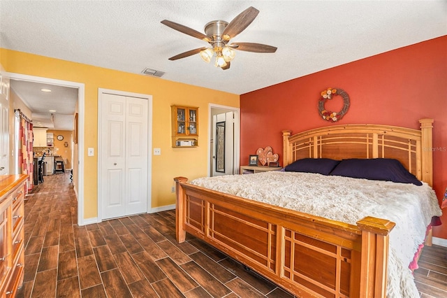 bedroom with wood finish floors, visible vents, baseboards, and a textured ceiling