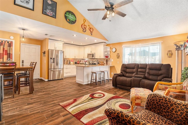 living room with dark wood-style floors, a ceiling fan, baseboards, high vaulted ceiling, and a textured ceiling