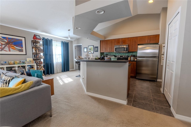 kitchen with brown cabinetry, vaulted ceiling, appliances with stainless steel finishes, dark countertops, and open floor plan