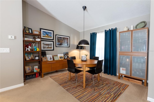 carpeted dining space with baseboards and lofted ceiling