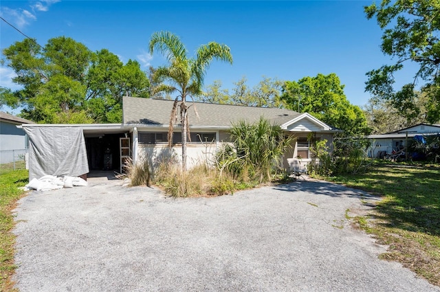 view of front of property featuring a front lawn, an attached carport, and driveway