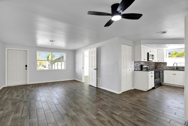 unfurnished living room with dark wood finished floors, visible vents, and a sink