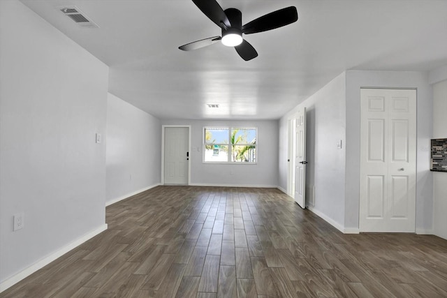 empty room with visible vents, a ceiling fan, dark wood-type flooring, and baseboards