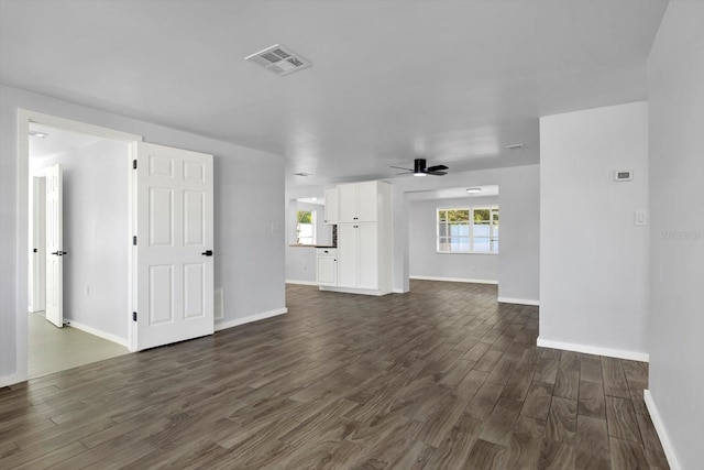 unfurnished living room with dark wood finished floors, a ceiling fan, visible vents, and baseboards