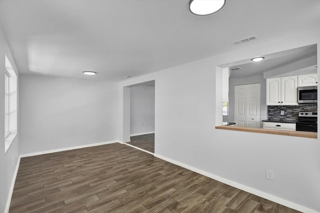 interior space with a wealth of natural light, baseboards, visible vents, and dark wood-style flooring