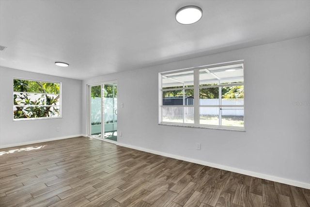 unfurnished room with baseboards, a healthy amount of sunlight, and wood finished floors