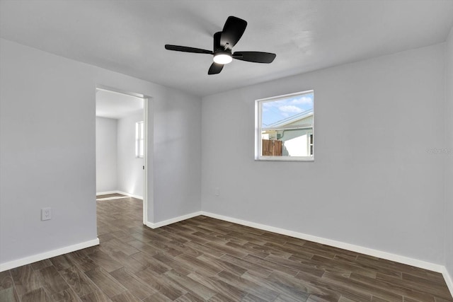 spare room with dark wood-style floors, a ceiling fan, and baseboards