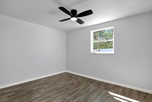 spare room featuring a ceiling fan, dark wood-style floors, and baseboards