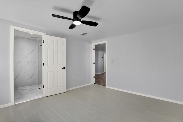 unfurnished bedroom with wood finished floors, baseboards, visible vents, ceiling fan, and connected bathroom