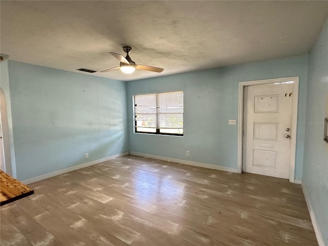 unfurnished room featuring a ceiling fan, wood finished floors, and baseboards