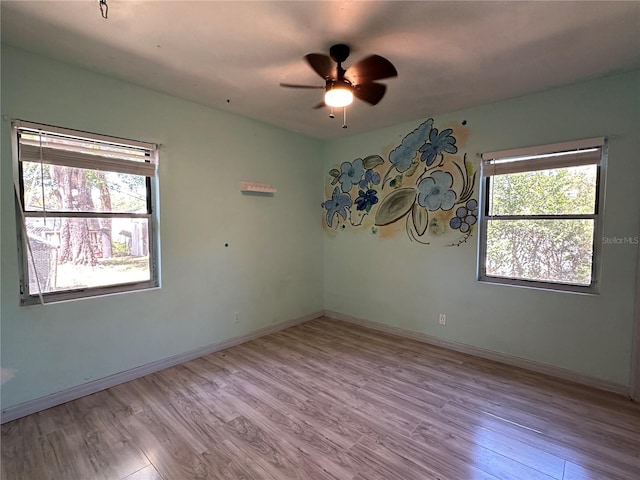 empty room featuring ceiling fan, baseboards, and wood finished floors