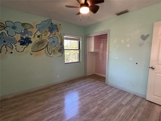 unfurnished bedroom featuring visible vents, baseboards, a closet, and wood finished floors