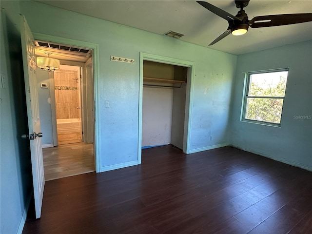 unfurnished bedroom featuring visible vents, baseboards, a closet, and dark wood-style floors