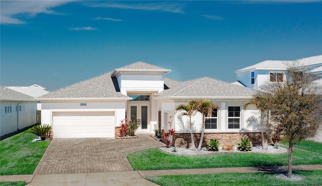 view of front of property with decorative driveway, an attached garage, roof with shingles, and stucco siding