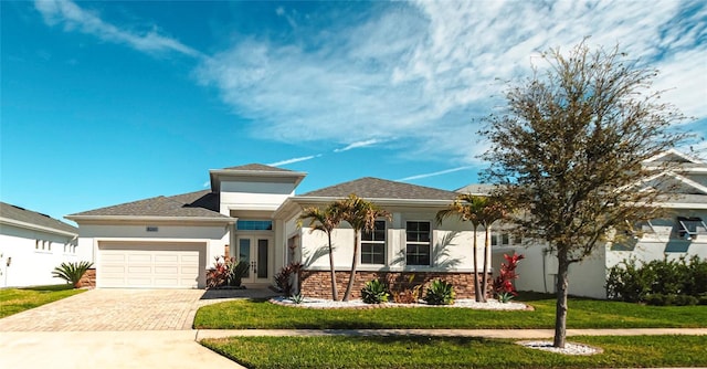 view of front of property featuring a front yard, decorative driveway, a garage, and stucco siding