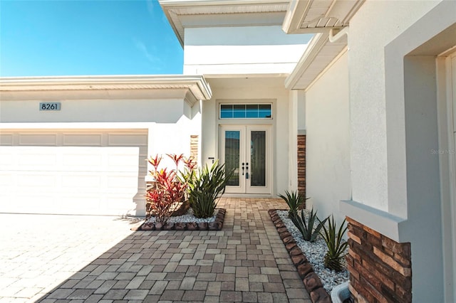 doorway to property featuring stucco siding, french doors, and an attached garage