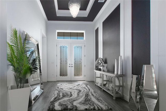 foyer entrance with ornamental molding, a tray ceiling, wood finished floors, french doors, and an inviting chandelier