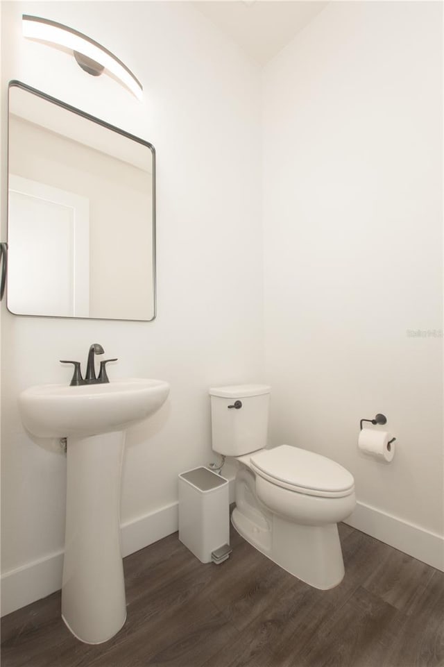 bathroom featuring toilet, wood finished floors, and baseboards