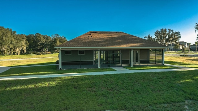 rear view of house with a yard and a sunroom