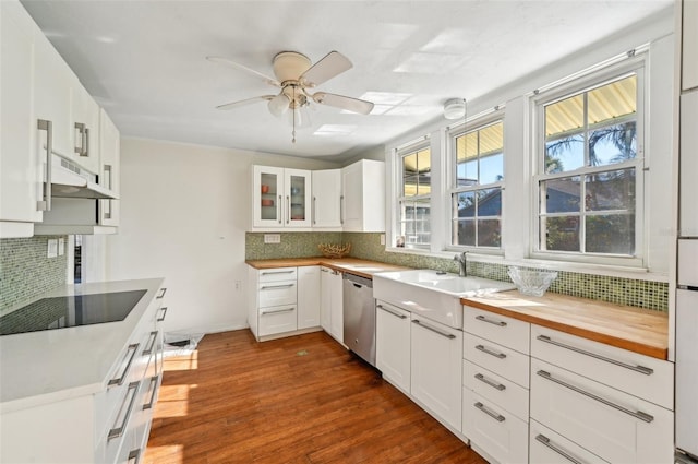 kitchen with dark wood-type flooring, under cabinet range hood, a sink, black electric stovetop, and dishwasher