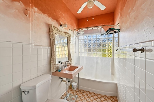 full bath featuring a ceiling fan, tub / shower combination, a sink, tile walls, and toilet