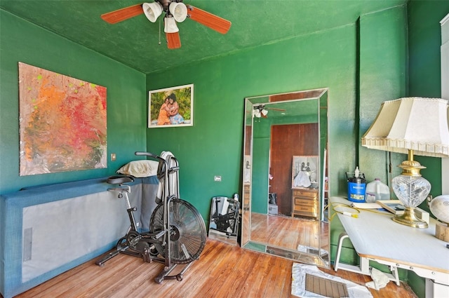 exercise room with ceiling fan and wood finished floors