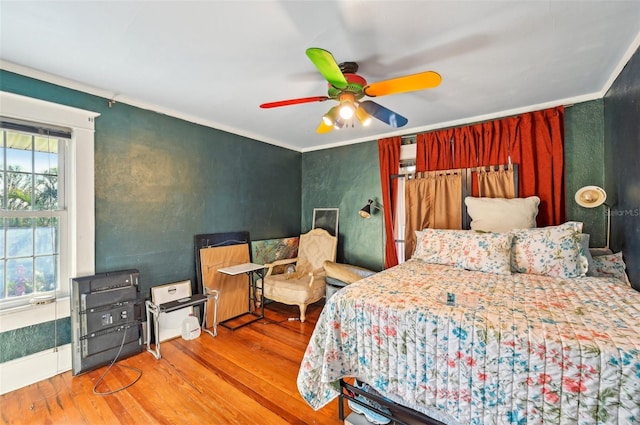 bedroom featuring a ceiling fan, wood finished floors, and ornamental molding