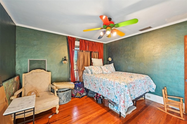 bedroom featuring visible vents, crown molding, and wood finished floors