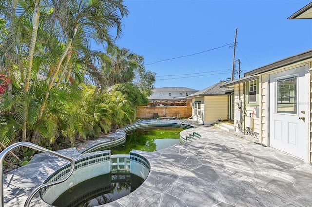 view of patio featuring a fenced in pool, an in ground hot tub, and fence