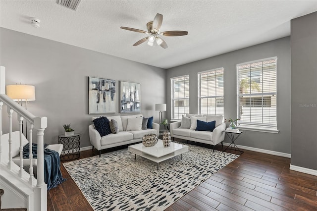 living area featuring a wealth of natural light, visible vents, dark wood-type flooring, and ceiling fan