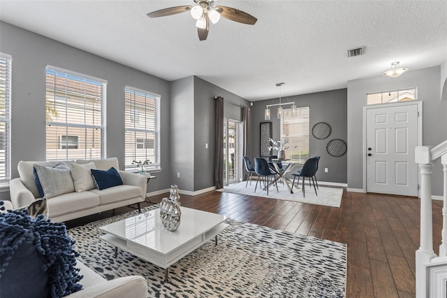 living room with visible vents, a ceiling fan, a textured ceiling, dark wood-style floors, and baseboards