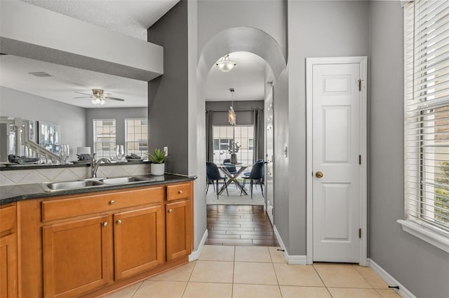 kitchen with a sink, a wealth of natural light, ceiling fan, and brown cabinetry