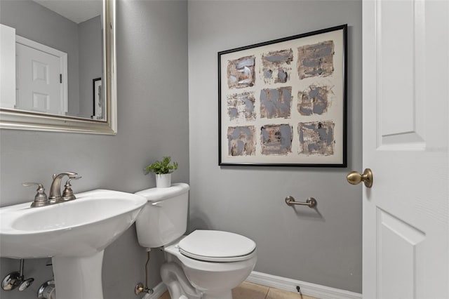 bathroom featuring a sink, baseboards, toilet, and tile patterned flooring